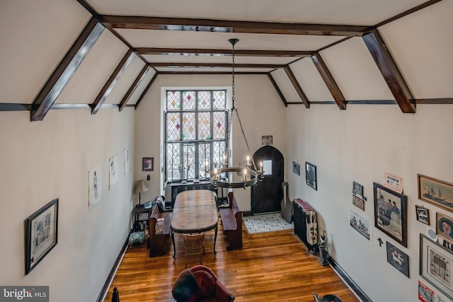 dining room featuring dark hardwood / wood-style flooring, vaulted ceiling with beams, and a chandelier