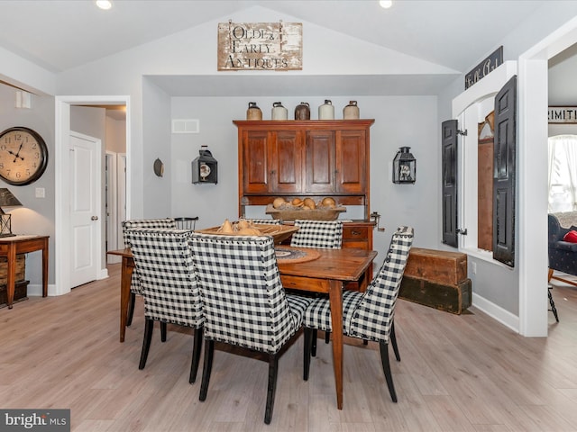 dining space with light hardwood / wood-style floors and vaulted ceiling