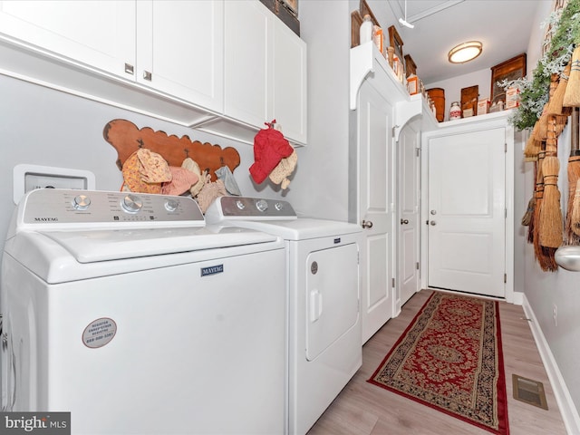 washroom featuring independent washer and dryer, cabinets, and light hardwood / wood-style floors