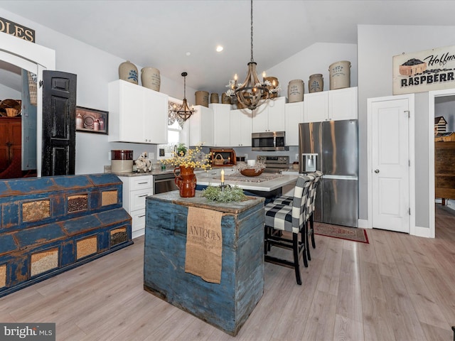 kitchen featuring stainless steel appliances, light hardwood / wood-style floors, pendant lighting, a kitchen island, and an inviting chandelier