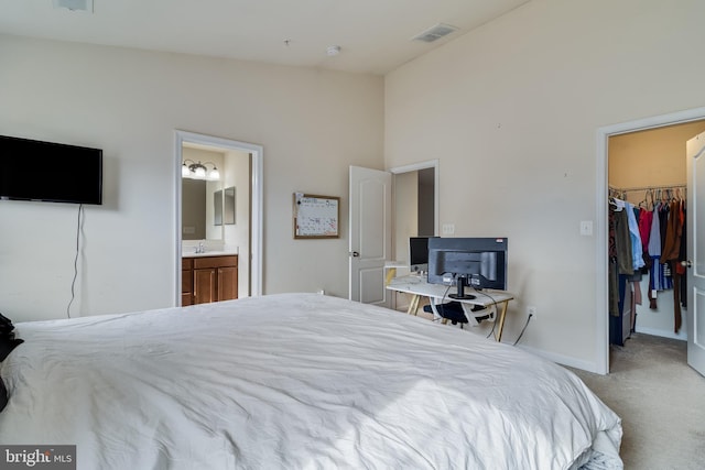 bedroom featuring light colored carpet, ensuite bathroom, a closet, and a walk in closet