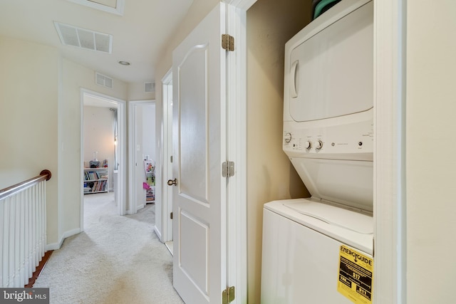 washroom featuring light colored carpet and stacked washer / dryer