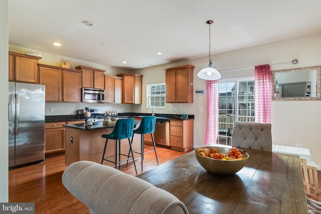 kitchen featuring wood-type flooring, stainless steel appliances, a kitchen breakfast bar, and a kitchen island