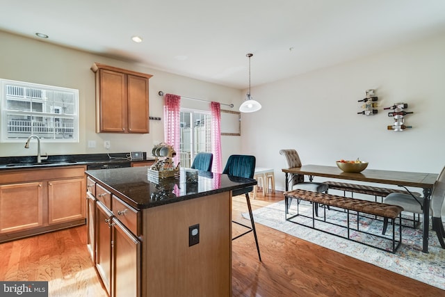 kitchen featuring pendant lighting, sink, a kitchen breakfast bar, a center island, and light hardwood / wood-style floors