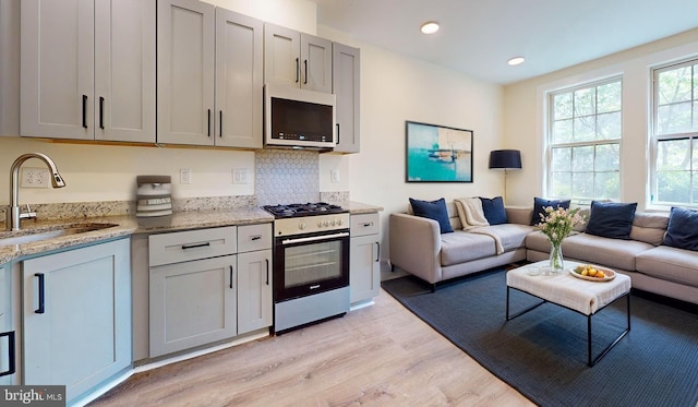 1821 T St NW, Washington, DC 20009 - kitchen featuring light wood-type flooring, open floor plan, a sink, and appliances with stainless steel finishes