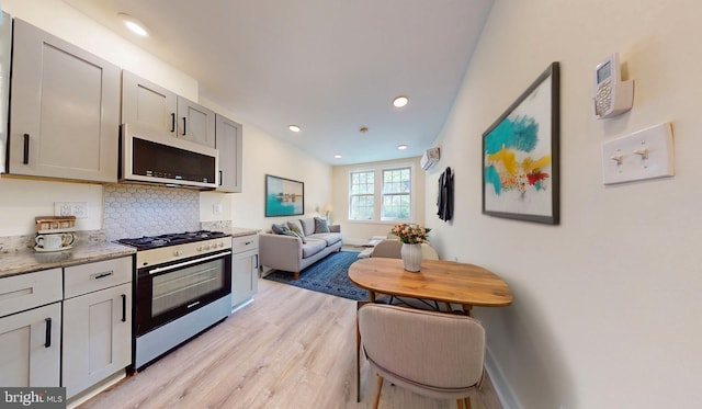 1821 T St NW, Washington, DC 20009 - kitchen with light wood finished floors, backsplash, gas stove, white microwave, and open floor plan