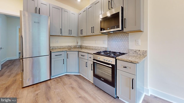 1821 T St NW, Washington, DC 20009 - kitchen with light stone counters, a sink, light wood finished floors, baseboards, and appliances with stainless steel finishes