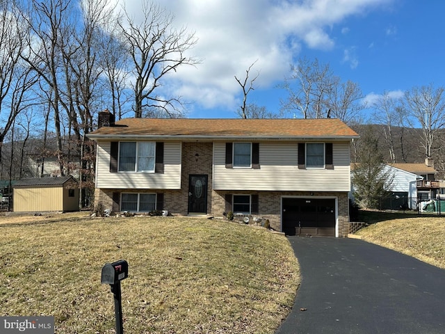 bi-level home featuring a garage, a storage unit, and a front lawn