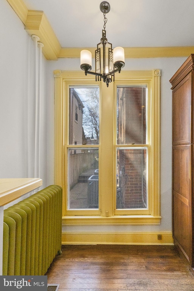 details with hardwood / wood-style flooring, crown molding, radiator, and a notable chandelier