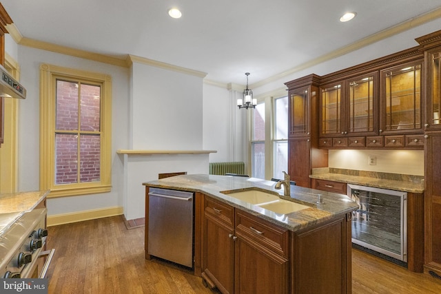 kitchen with sink, stainless steel appliances, a center island with sink, decorative light fixtures, and beverage cooler