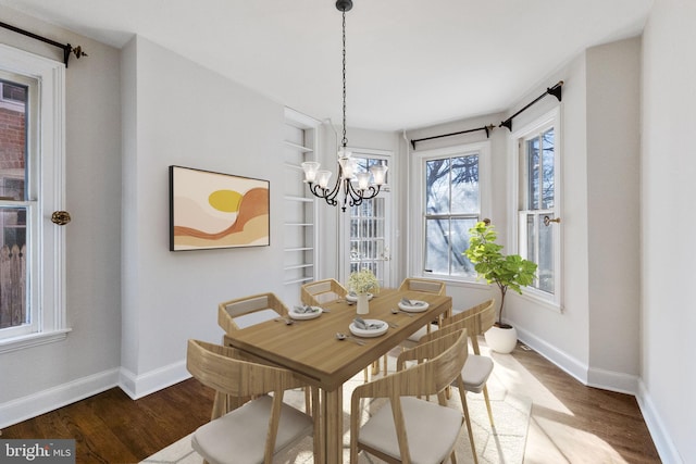 dining space with hardwood / wood-style floors, built in features, and a notable chandelier