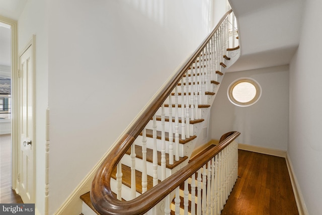 stairs featuring wood-type flooring and a high ceiling