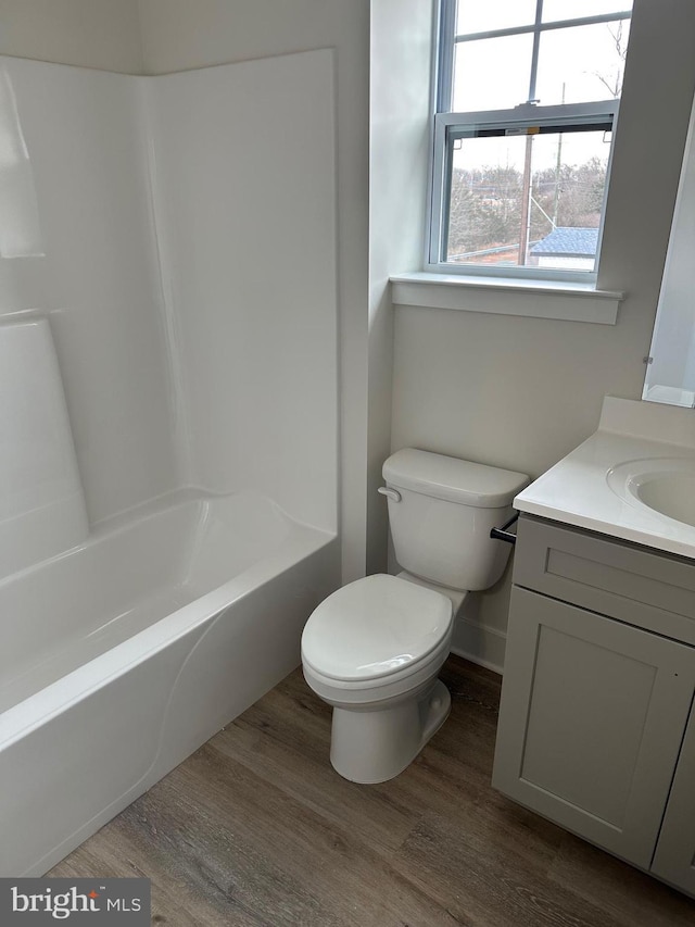 bathroom with toilet, shower / bathing tub combination, wood finished floors, and vanity