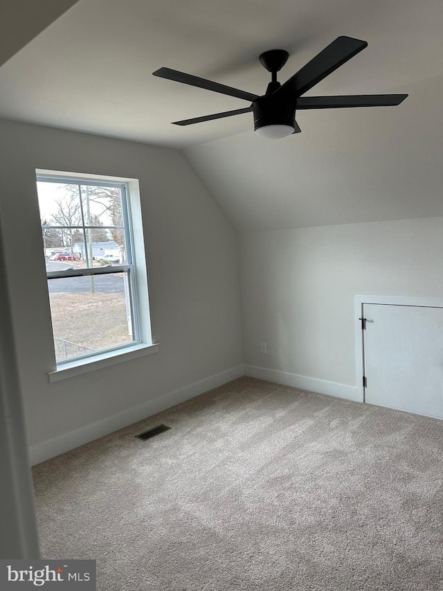 additional living space featuring lofted ceiling, visible vents, baseboards, a ceiling fan, and carpet