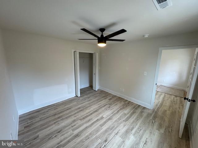 unfurnished room featuring light wood-type flooring, visible vents, ceiling fan, and baseboards