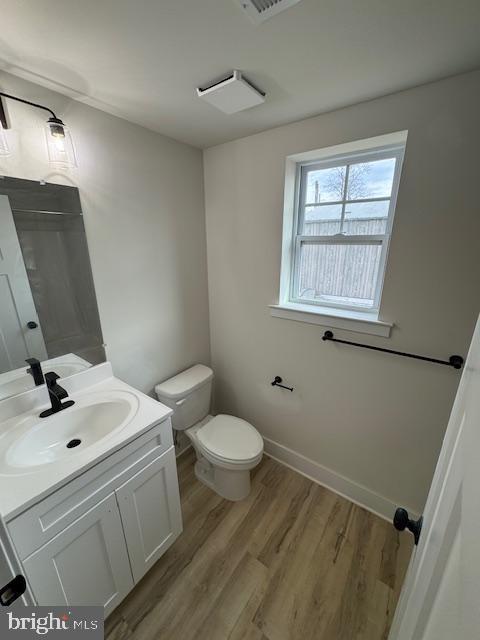 bathroom featuring toilet, wood finished floors, vanity, and baseboards