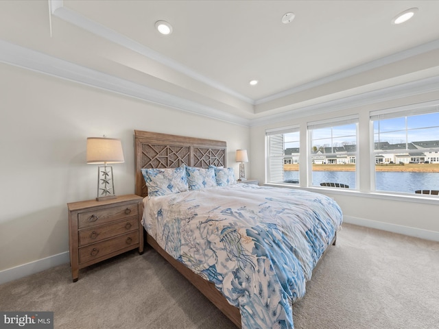 carpeted bedroom featuring a raised ceiling, ornamental molding, and a water view