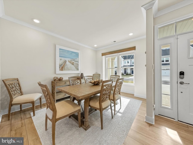 dining area with ornamental molding and light hardwood / wood-style floors