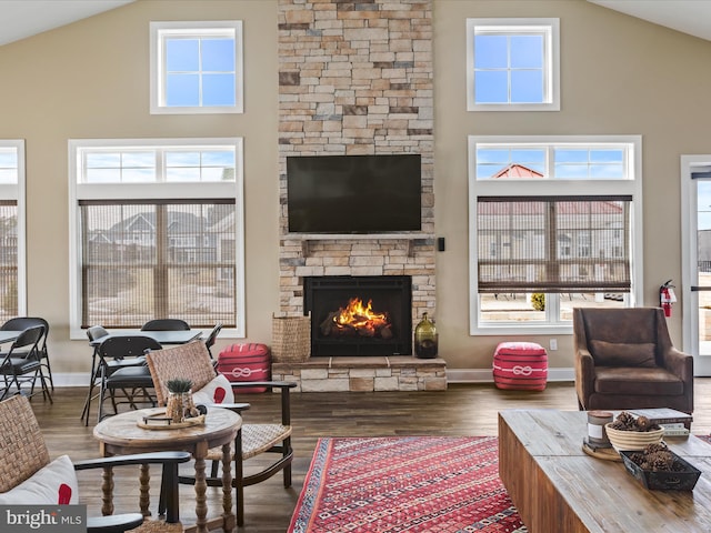 living room with dark hardwood / wood-style flooring, a stone fireplace, and high vaulted ceiling