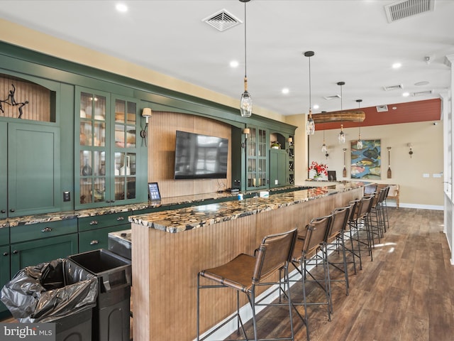 bar with green cabinetry, dark stone counters, dark hardwood / wood-style floors, and hanging light fixtures