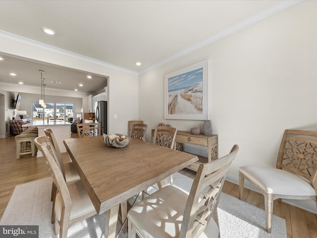 dining area with ornamental molding and light hardwood / wood-style floors