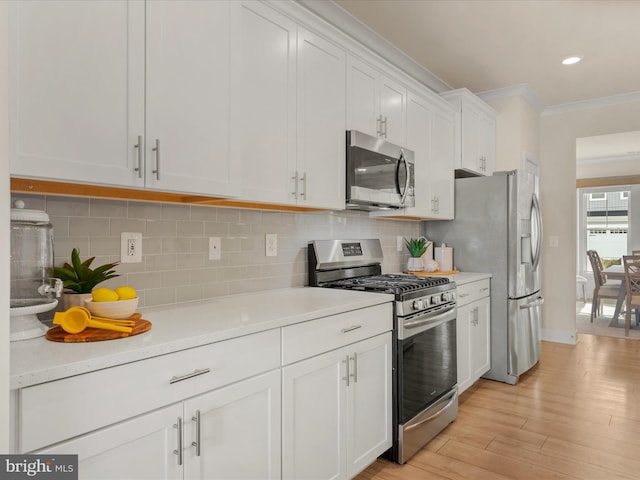 kitchen with light hardwood / wood-style flooring, ornamental molding, white cabinets, stainless steel appliances, and backsplash