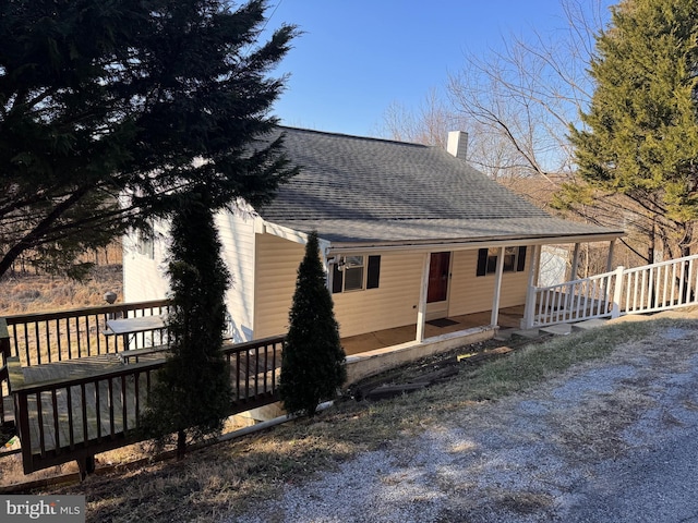 exterior space featuring roof with shingles and a chimney