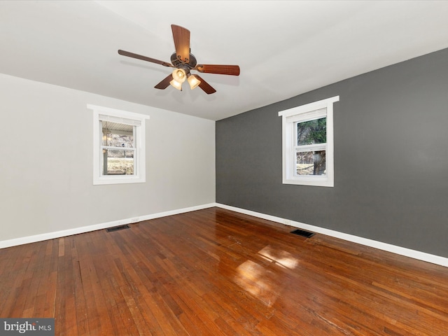 unfurnished room with a ceiling fan, wood-type flooring, visible vents, and baseboards