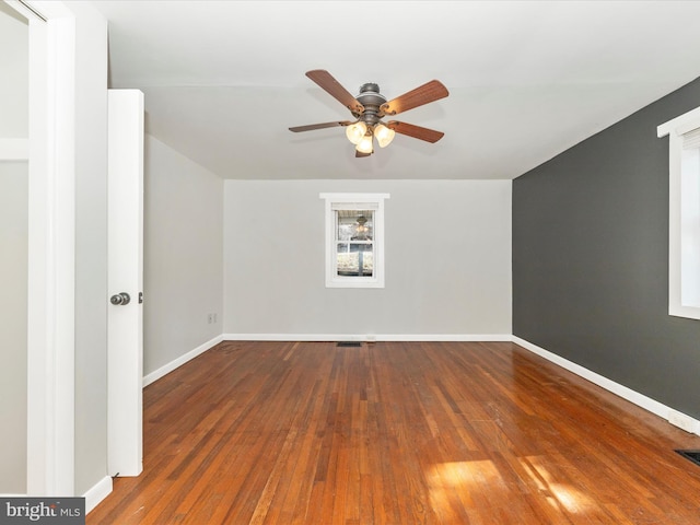 interior space with dark wood-type flooring, visible vents, baseboards, and a ceiling fan