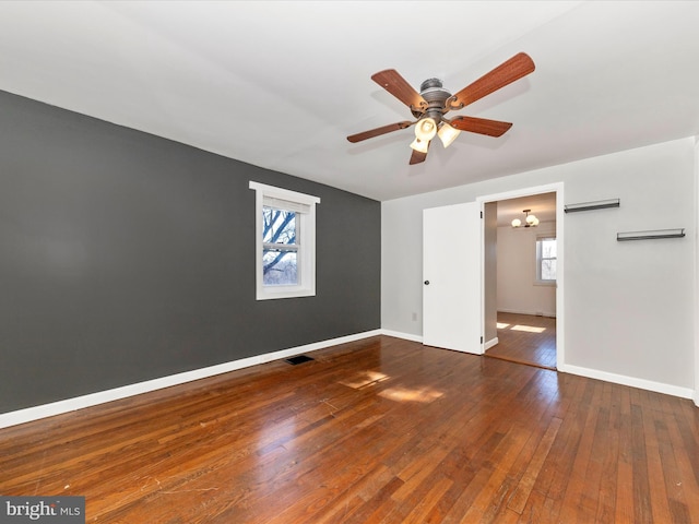 unfurnished bedroom featuring dark wood-style floors, visible vents, baseboards, and ceiling fan