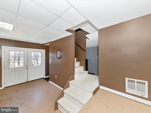 foyer entrance with a paneled ceiling, visible vents, finished concrete floors, baseboards, and stairs