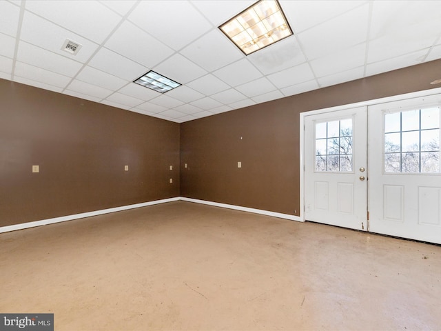 foyer entrance featuring french doors, visible vents, a drop ceiling, concrete floors, and baseboards