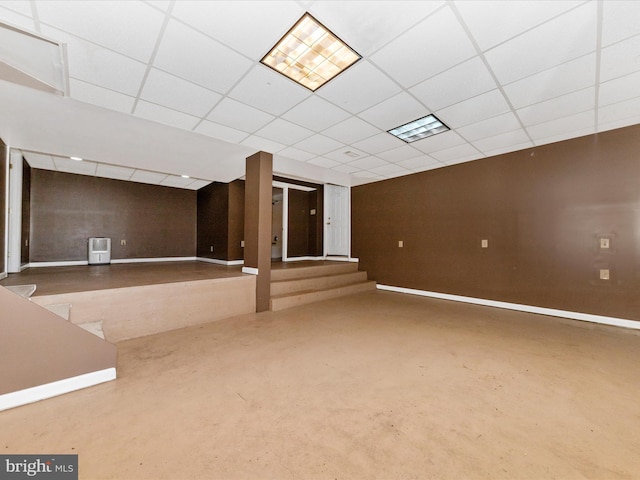 finished below grade area featuring a paneled ceiling and baseboards