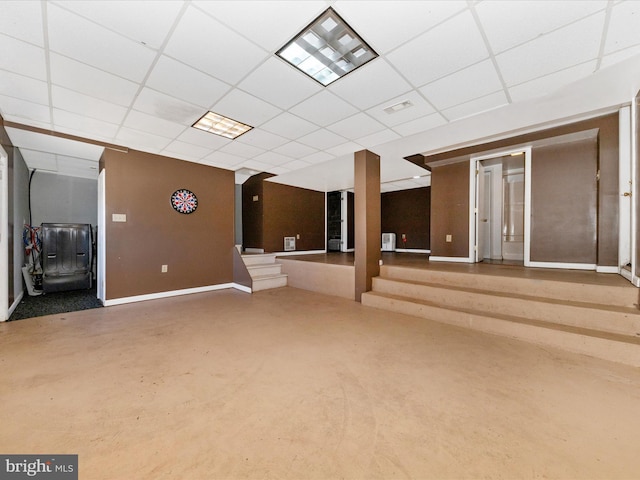 empty room featuring concrete flooring, a drop ceiling, visible vents, baseboards, and stairs