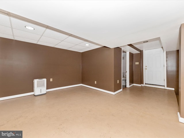 spare room featuring a paneled ceiling, concrete floors, baseboards, and recessed lighting