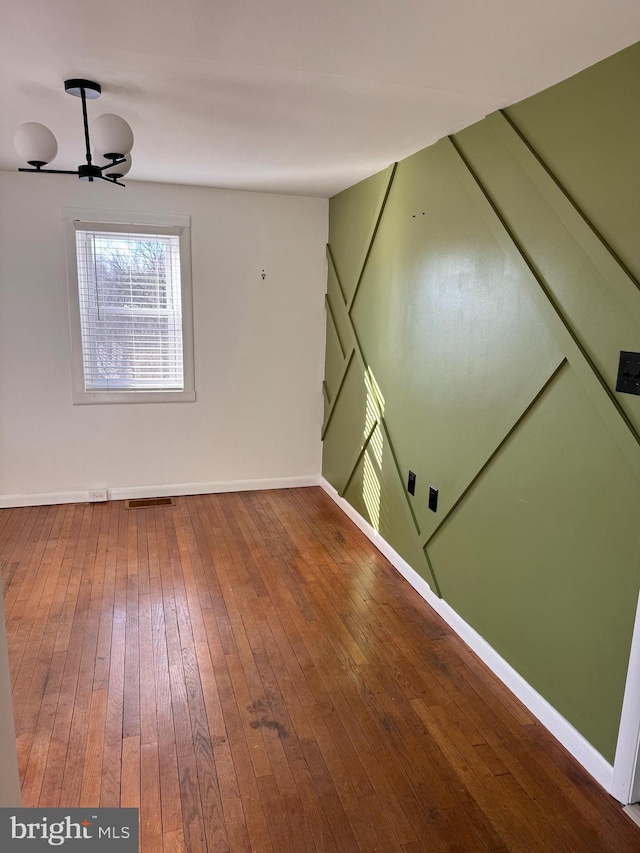 spare room with visible vents, baseboards, and hardwood / wood-style flooring