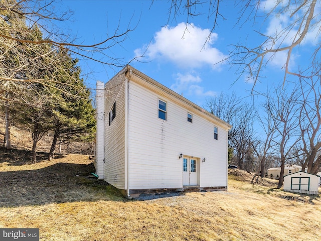 view of side of home featuring a yard, a shed, and an outdoor structure