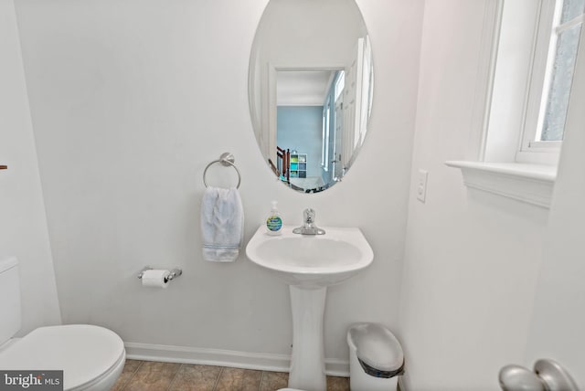 half bath featuring baseboards and toilet