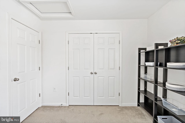 interior space with attic access, a closet, light carpet, and baseboards