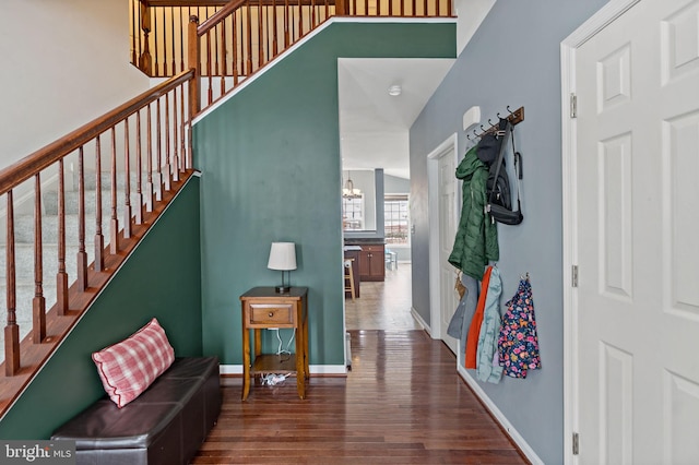 interior space featuring baseboards, dark wood-style floors, a notable chandelier, and stairway