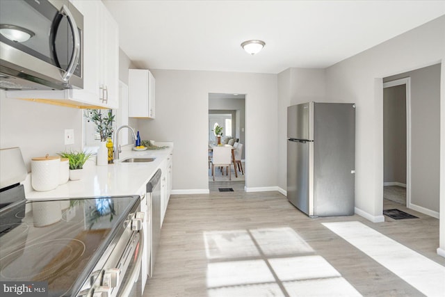 kitchen with white cabinetry, sink, light hardwood / wood-style flooring, and appliances with stainless steel finishes