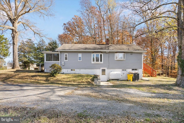 view of property exterior with a sunroom, central air condition unit, and a lawn