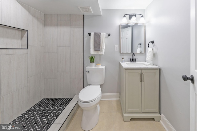 bathroom featuring tiled shower, vanity, toilet, and tile patterned flooring