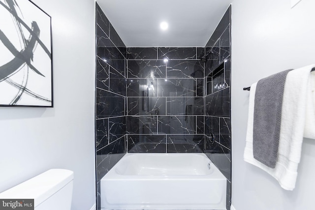 bathroom featuring tiled shower / bath combo and toilet