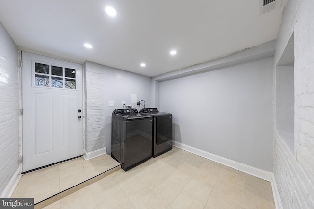 laundry area with washing machine and dryer and brick wall