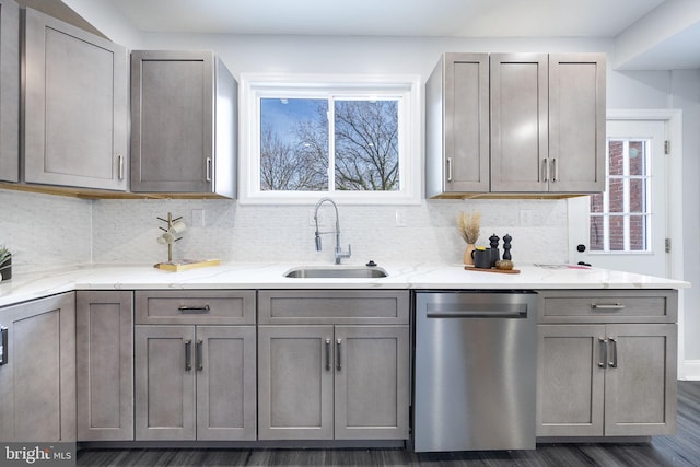 kitchen with dishwasher, light stone countertops, sink, and decorative backsplash