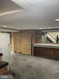 basement with white fridge and a textured ceiling