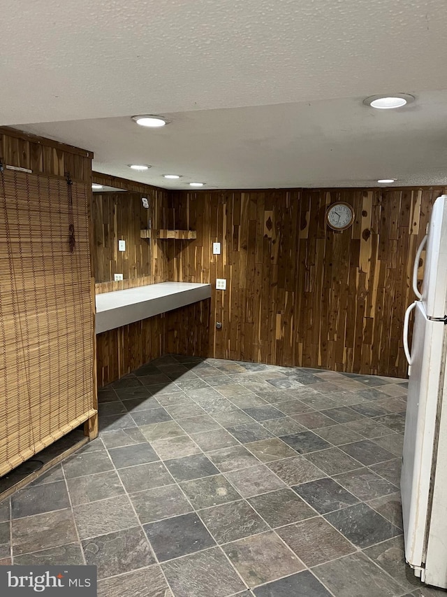 bar featuring white refrigerator, wooden walls, and a textured ceiling