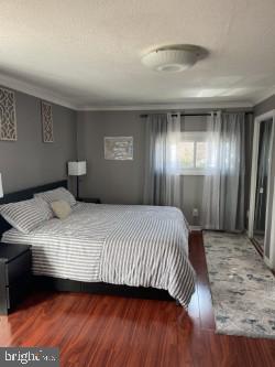 bedroom with crown molding and dark wood-type flooring