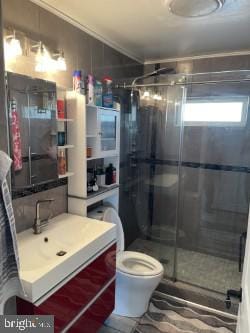 bathroom with walk in shower, vanity, and toilet